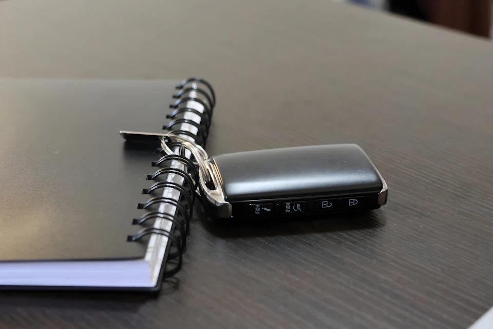 Car key beside a notebook on a desk